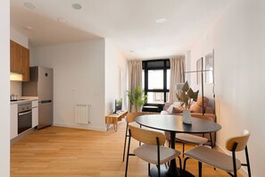 Una cocina moderna con comedor, piso de madera y un amplio ventanal con cortinas.