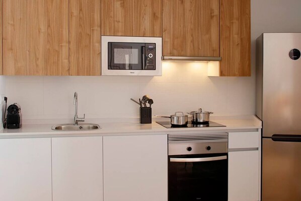 A modern kitchen with wooden cabinets, a microwave, a sink, a stove, and a dishwasher.