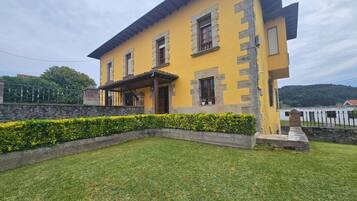 A yellow building with a stone facade, a covered porch, and a well-maintained lawn.