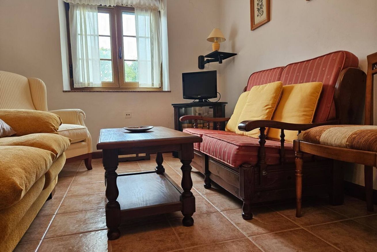 Una sala de estar con sofá, sillón, mesa y televisor.