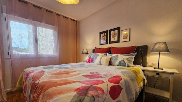 A hotel room with a bed, a nightstand, a lamp, and a window with curtains. - 645A Coqueto apartamento en Oviedo (Oviedo)