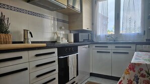 Una cocina moderna con gabinetes blancos, estufa de acero inoxidable y microondas.