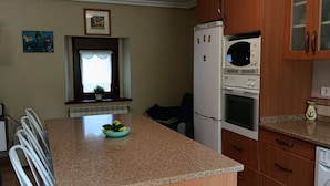 Eine Küche mit Granitabdeckung, einem Kühlschrank, einer Mikrowelle und Holzschränken.