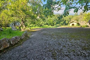 A gravel path leading to a rustic building surrounded by greenery and trees. - 13A05 La Casina en Sebreño (Ribadesella)