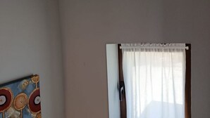 Ein Zimmer mit Fenster, Tür und einer Wand, die einen ungehinderten Blick auf ein Gemälde bietet.