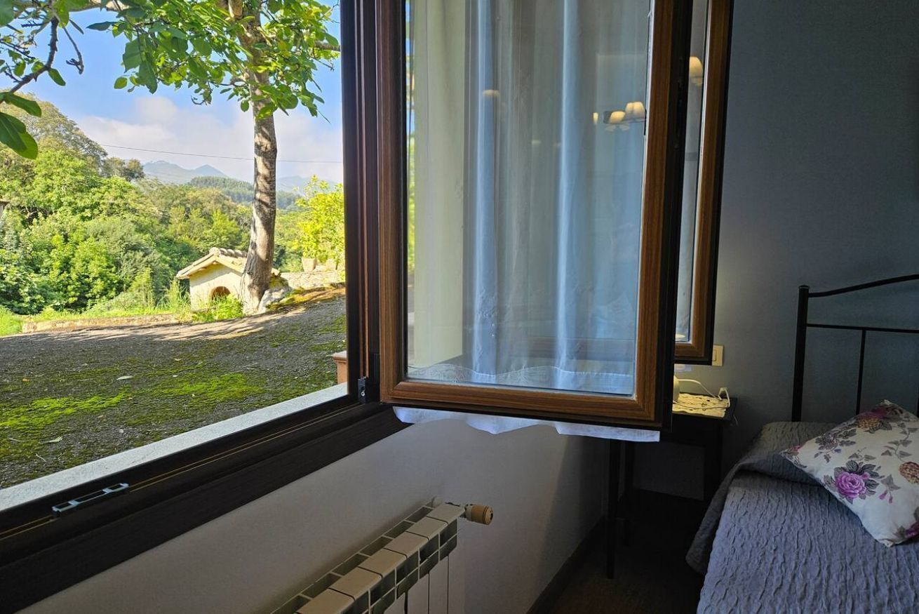 Une chambre avec une fenêtre, un radiateur et un lit agrémenté d’un coussin à motifs floraux.