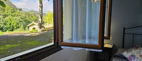 A bedroom with a window, a radiator, and a bed with a floral pillow.