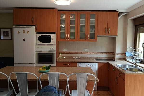 A kitchen with wooden cabinets, a refrigerator, microwave, oven, and a dishwasher.