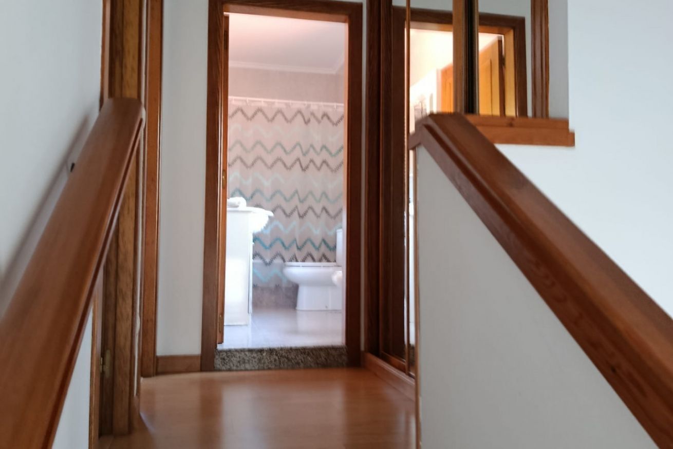 A wooden staircase leading to a bathroom with a patterned shower curtain.