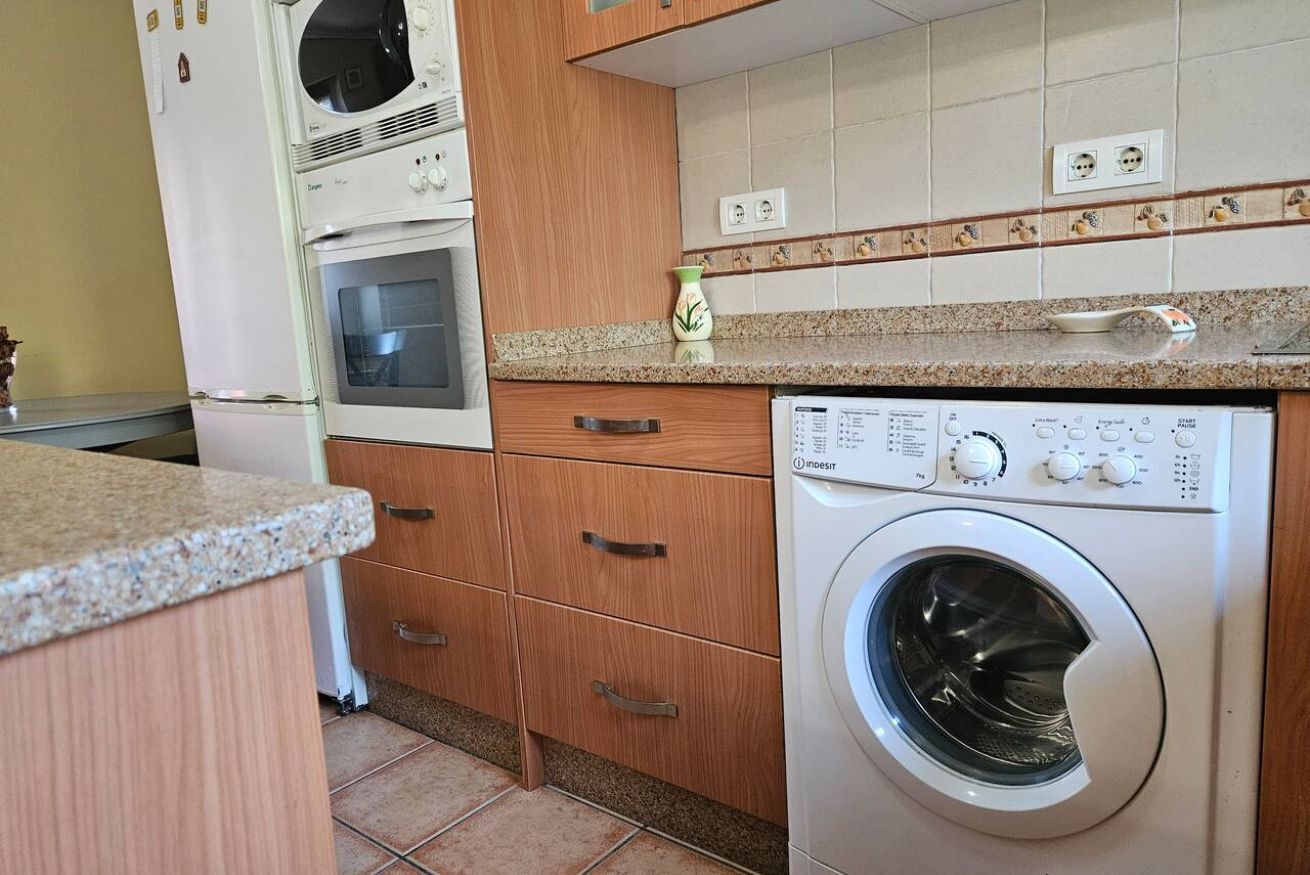 Cocina equipada con lavadora, horno y muebles de madera.