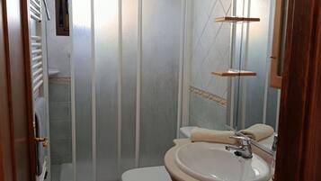 Une salle de bain avec des toilettes, un lavabo et une douche.