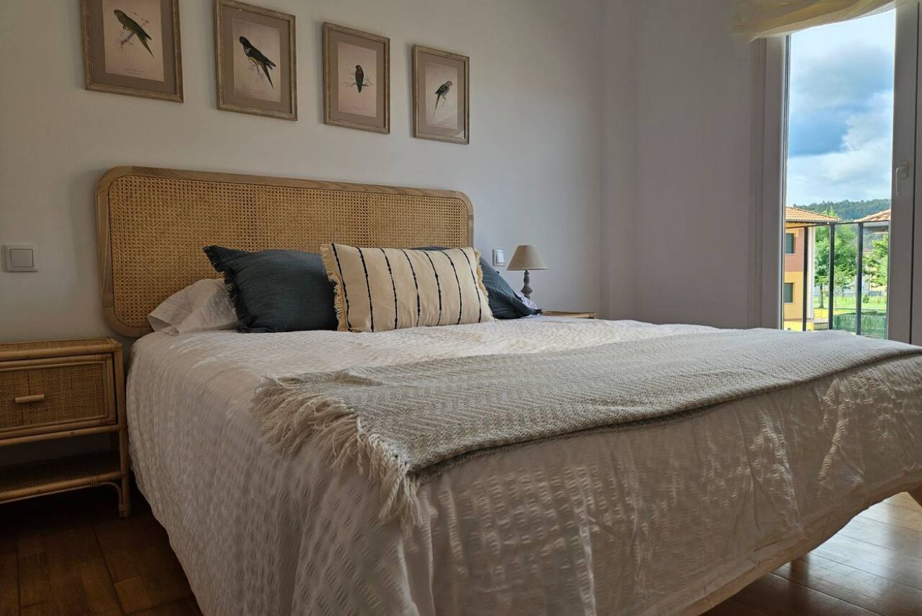 Un dormitorio con una cama grande, una mesita de noche, una lámpara y cuadros con pájaros en la pared.