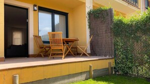 A patio with a table and chairs, a sliding glass door, and a wooden fence.