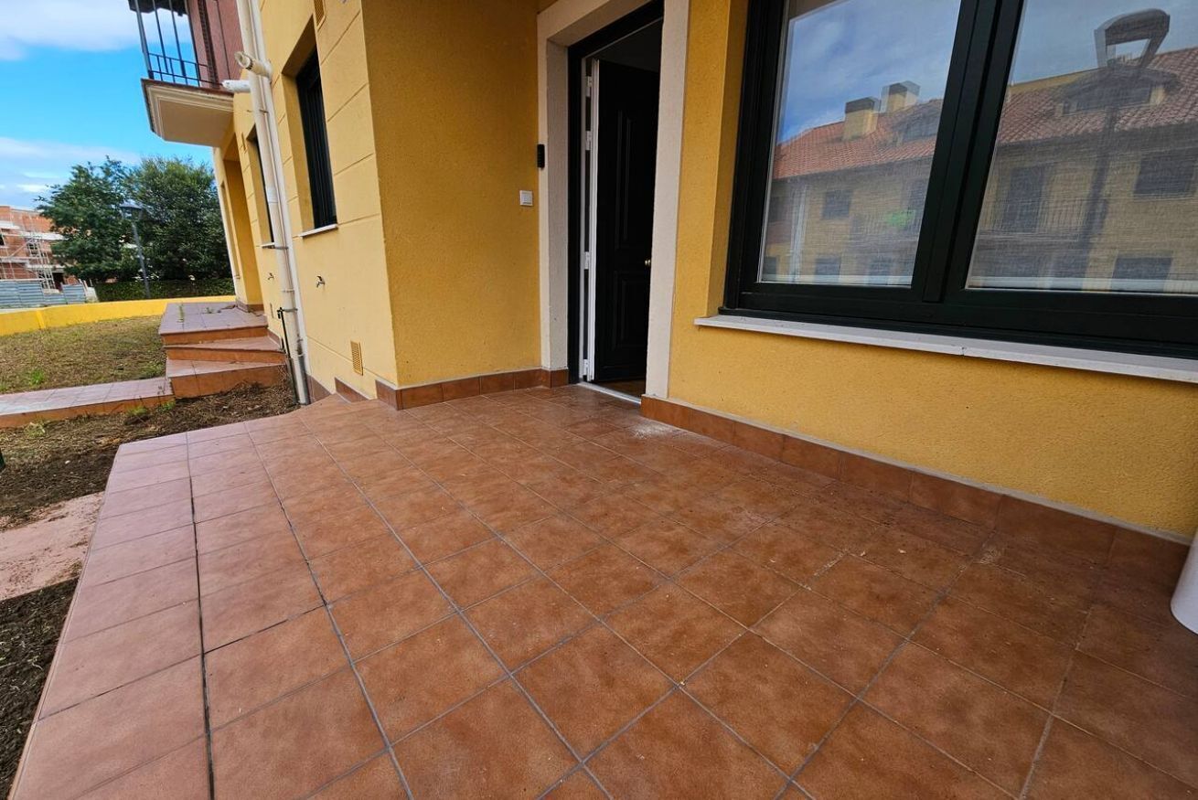 Un bâtiment à la façade jaune, doté d’une terrasse carrelée et d’une fenêtre.