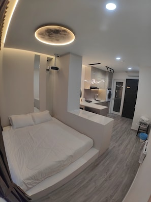 A modern bedroom with a large bed, a built-in desk, and a mirror.