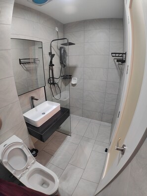 Un baño moderno con un lavamanos blanco, cabina de ducha de vidrio y un inodoro.