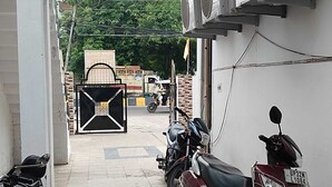 A narrow alleyway with parked motorcycles and scooters, a gated entrance, and a building with air conditioning units. - WoodStock Homestay By GRB (Lucknow)