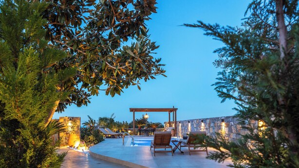 A poolside area with lounge chairs, a pergola, and stone walls. - KaYa SeaView Residence (Mylopotamos)