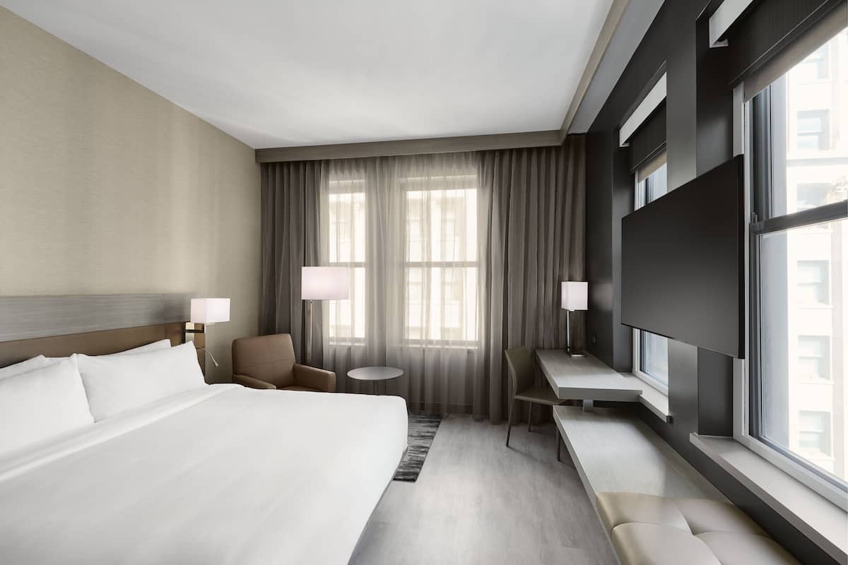 Une chambre d’hôtel avec un grand lit, un bureau, une chaise et un téléviseur.