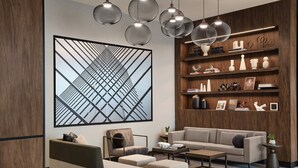 A modern living room with a sofa, armchairs, a coffee table, and a bookshelf. - AC Hotel by Marriott Kansas City Downtown (Kansas City)