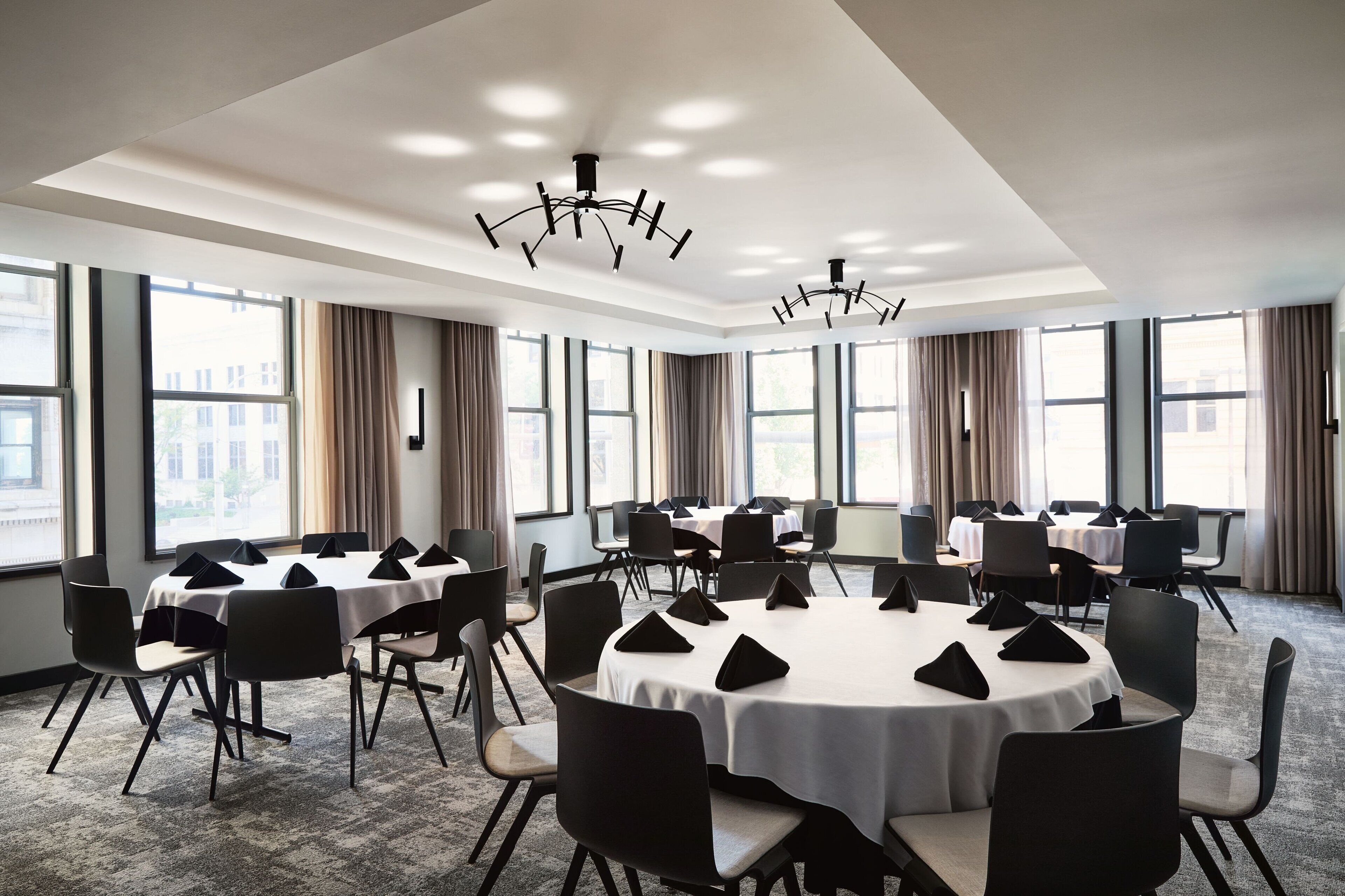 A conference room with round tables, chairs, and a chandelier.