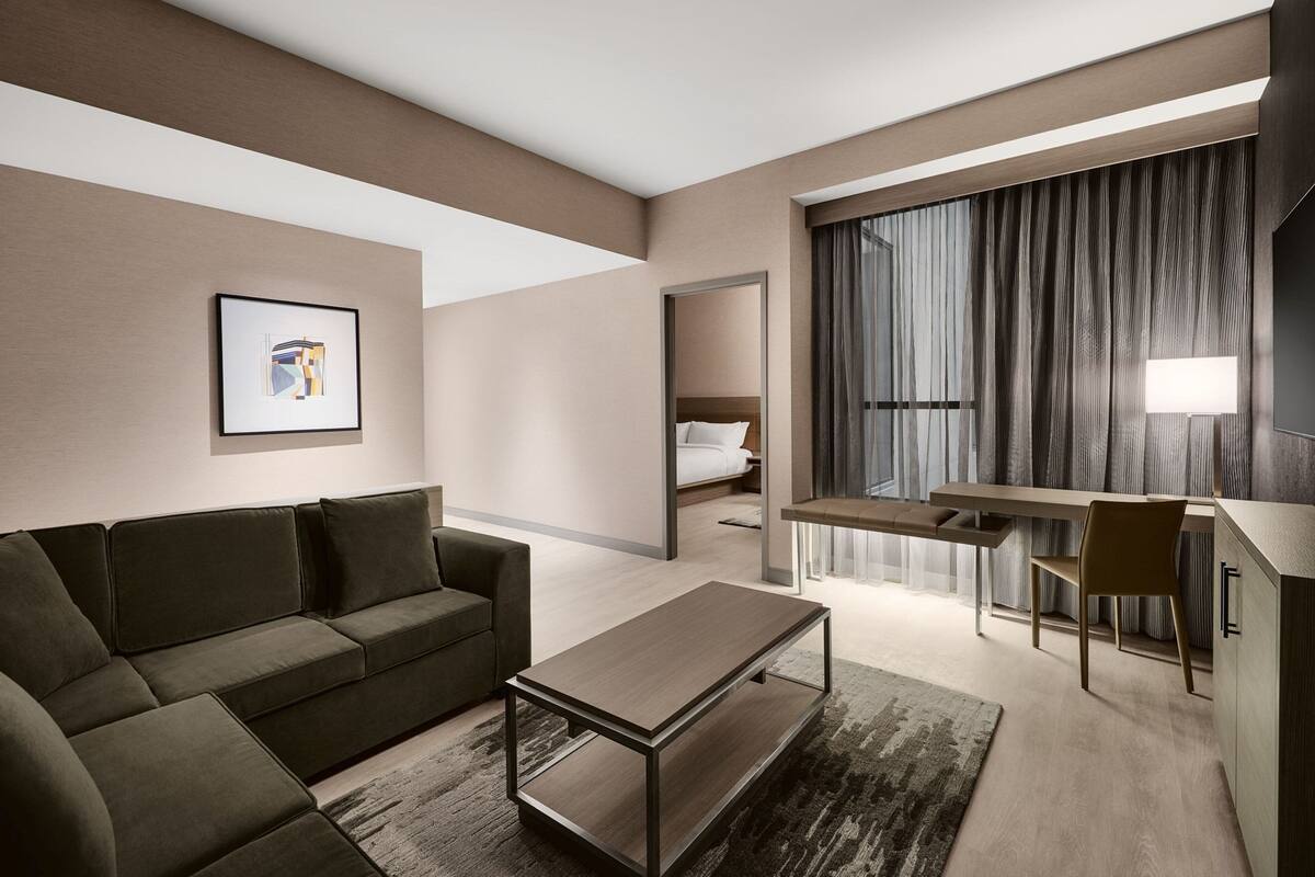 Une chambre d’hôtel moderne équipée d’un canapé, d’une table à manger, d’un petit coin cuisine et d’un lit.