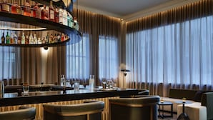 A modern bar area with a curved liquor display, a bar counter, and seating with a view of large windows. - AC Hotel by Marriott Kansas City Downtown (Kansas City)