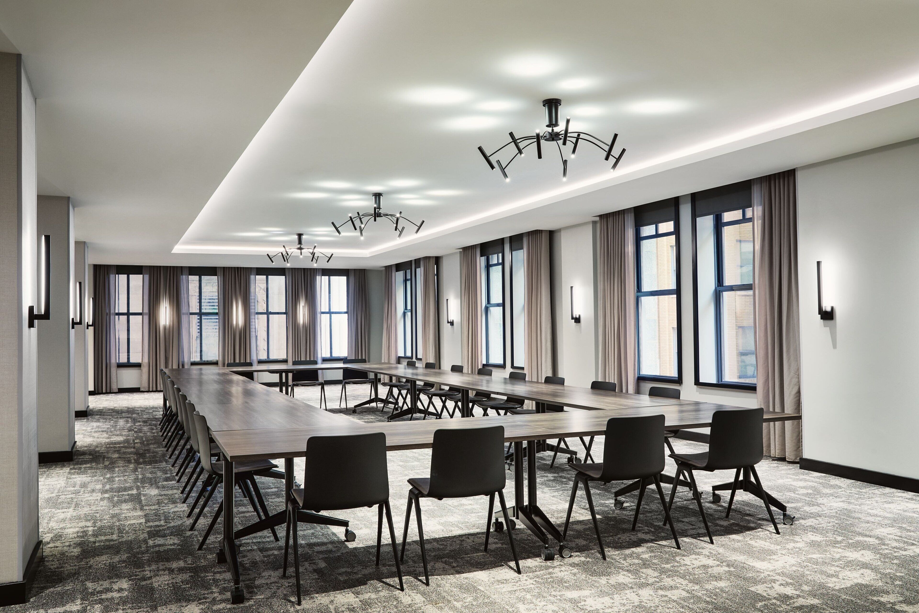 A conference room with a long table, multiple chairs, and large windows with curtains.
