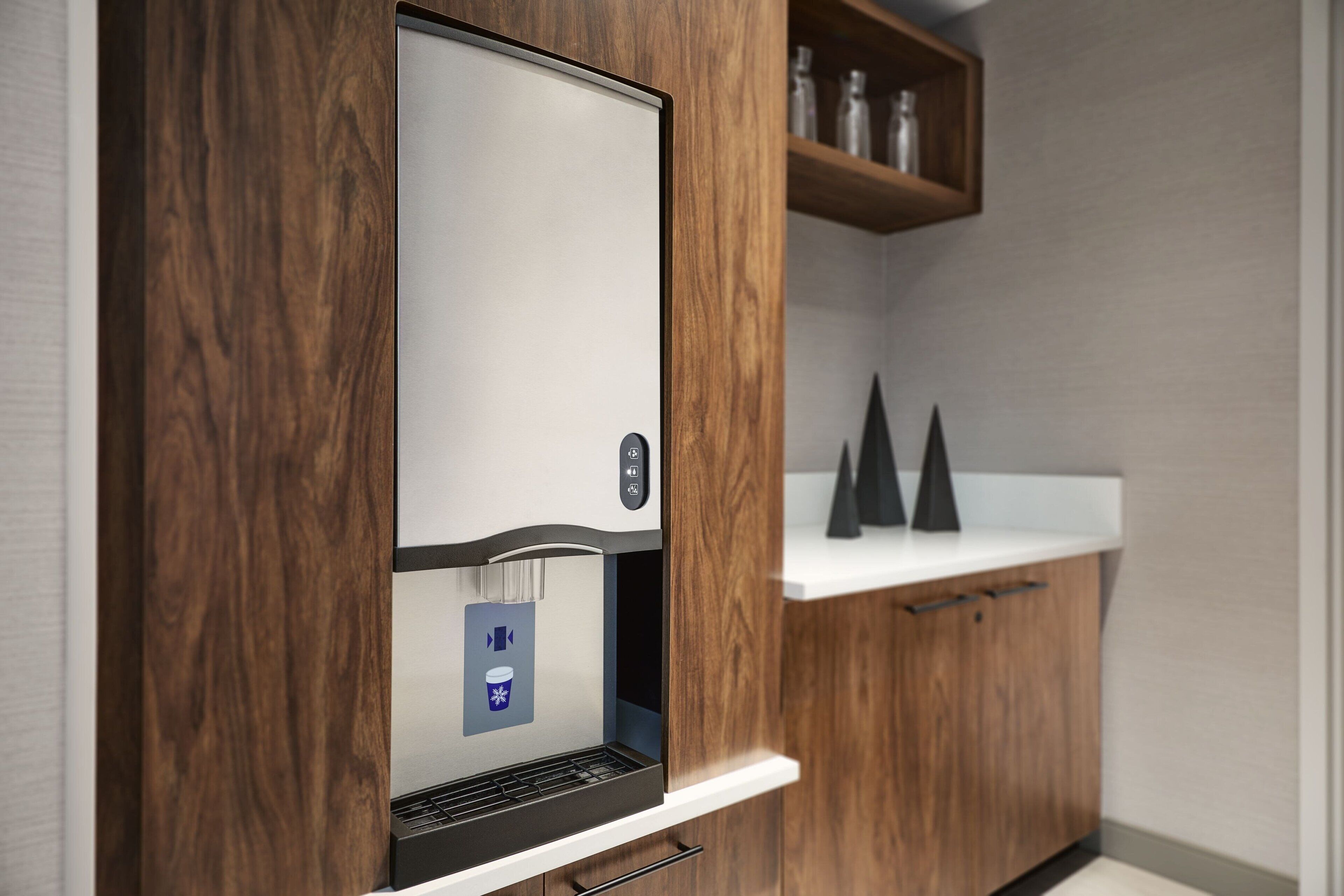 A coffee machine in a wooden cabinet with a white countertop and a shelf above it.