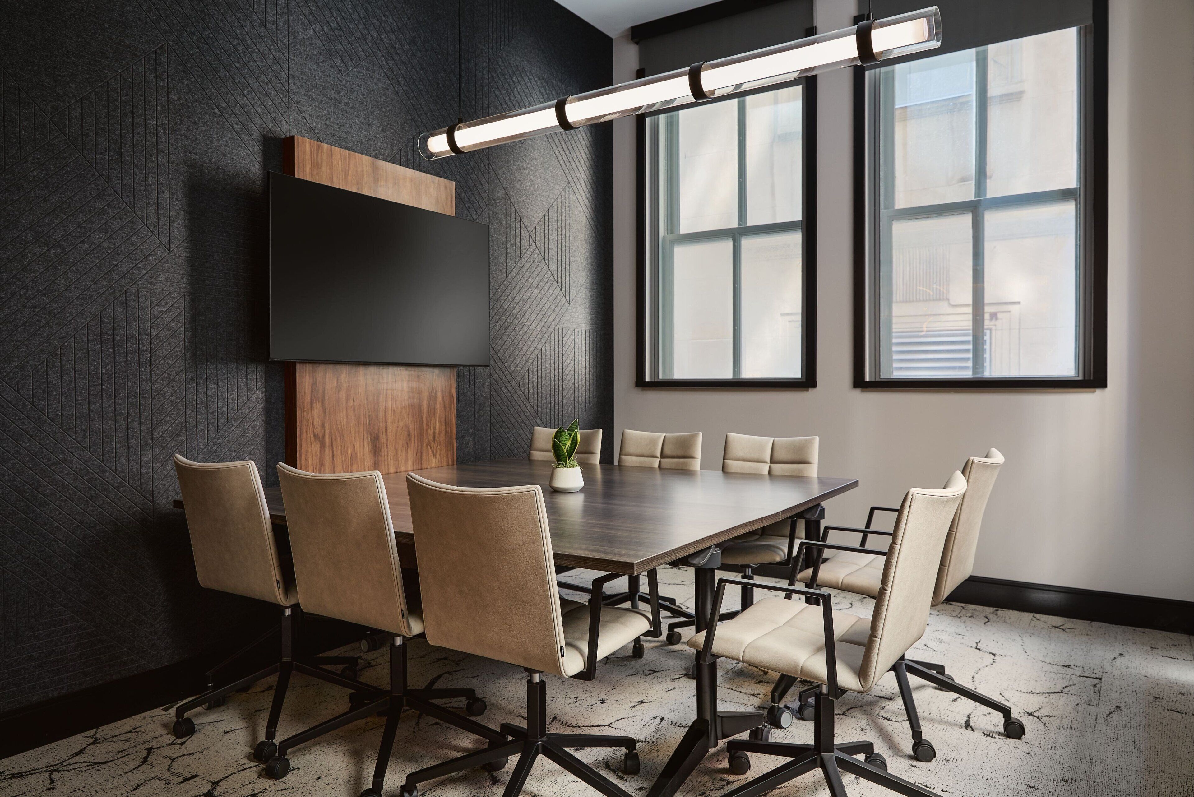 A conference room with a dark textured wall, a large table, and six chairs.