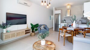 Una sala de estar moderna con un televisor de pantalla plana, muebles de madera y un comedor con mesa y sillas.