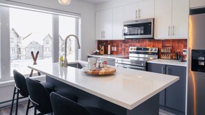 Une cuisine moderne dotée d’un îlot central, d’appareils électroménagers en acier inoxydable et offrant une vue sur la ville.