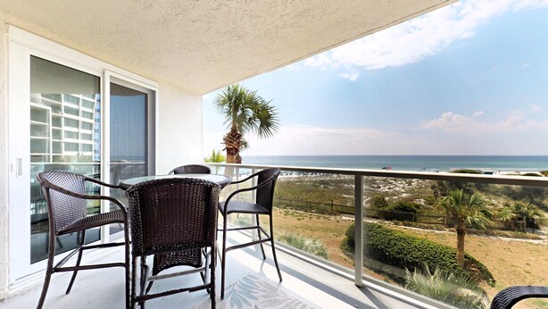A balcony with wicker chairs and a table, overlooking a beach and ocean. - Beachside II 4226 (Miramar Beach)