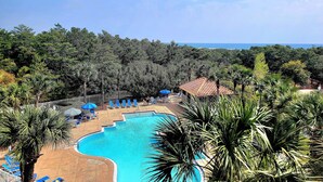 A swimming pool surrounded by palm trees and blue lounge chairs. - Summit 0409 (Miramar Beach)