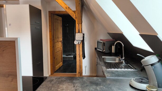 Una cocina compacta equipada con microondas, un lavabo y un hervidor.