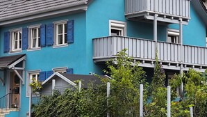 Un edificio azul con balcón y ventana con persianas.