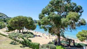 A beach with trees, a clear sky, and a calm sea. - RESIDENCIAL ALMADRAVA 4  Roses (Rosas / Roses)