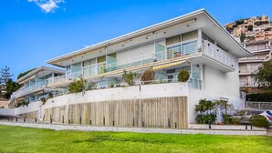 A modern multi-story building with balconies, a flat roof, and a wooden fence. - RESIDENCIAL ALMADRAVA 4  Roses (Rosas / Roses)