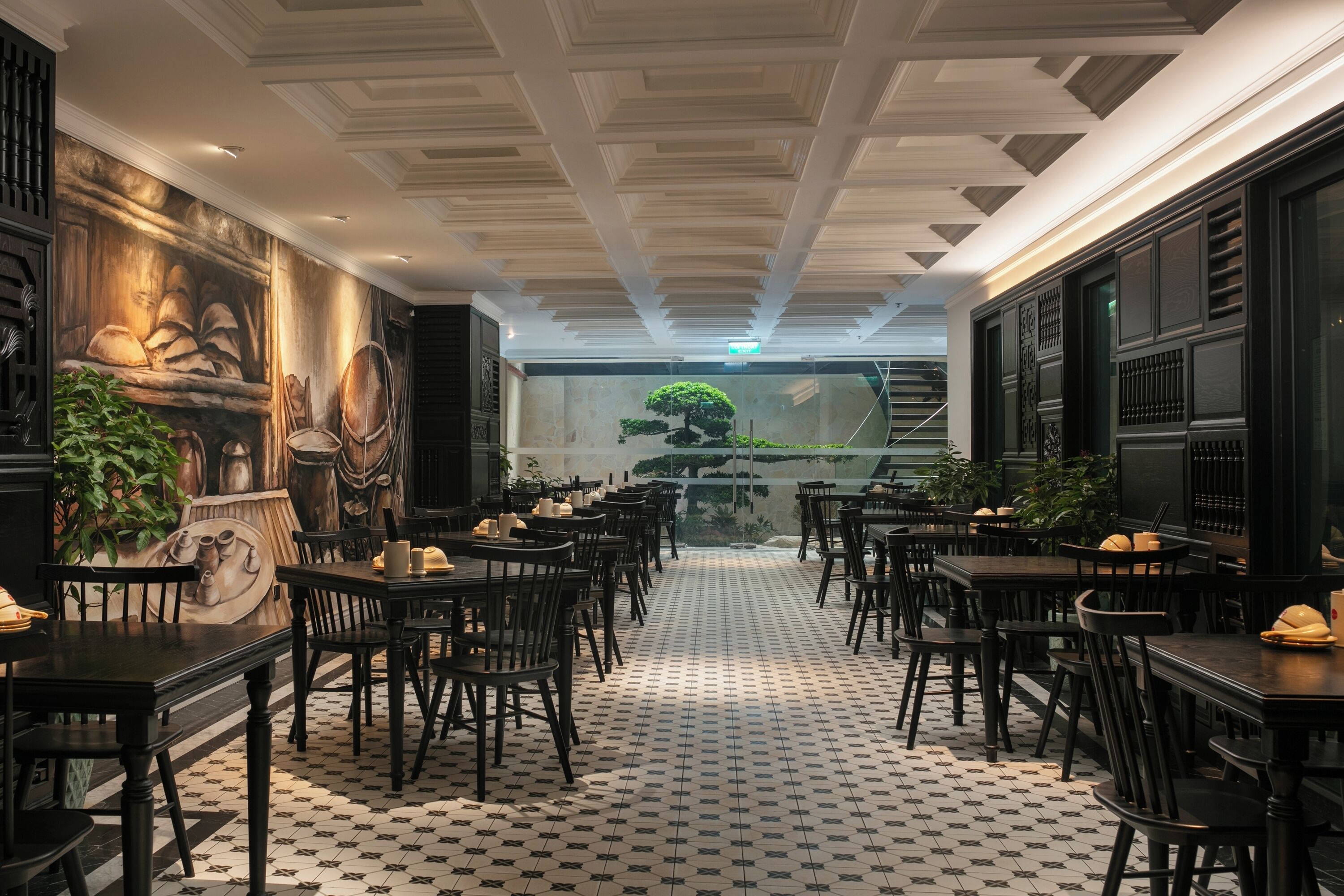 A restaurant with a checkered floor, black and white patterned walls, and a central view of a staircase leading to a balcony.