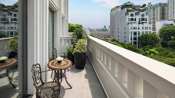 Ein Balkon mit Blick auf die Stadtlandschaft, ausgestattet mit einem Tisch, Stühlen, Topfpflanzen und einer Glastür.