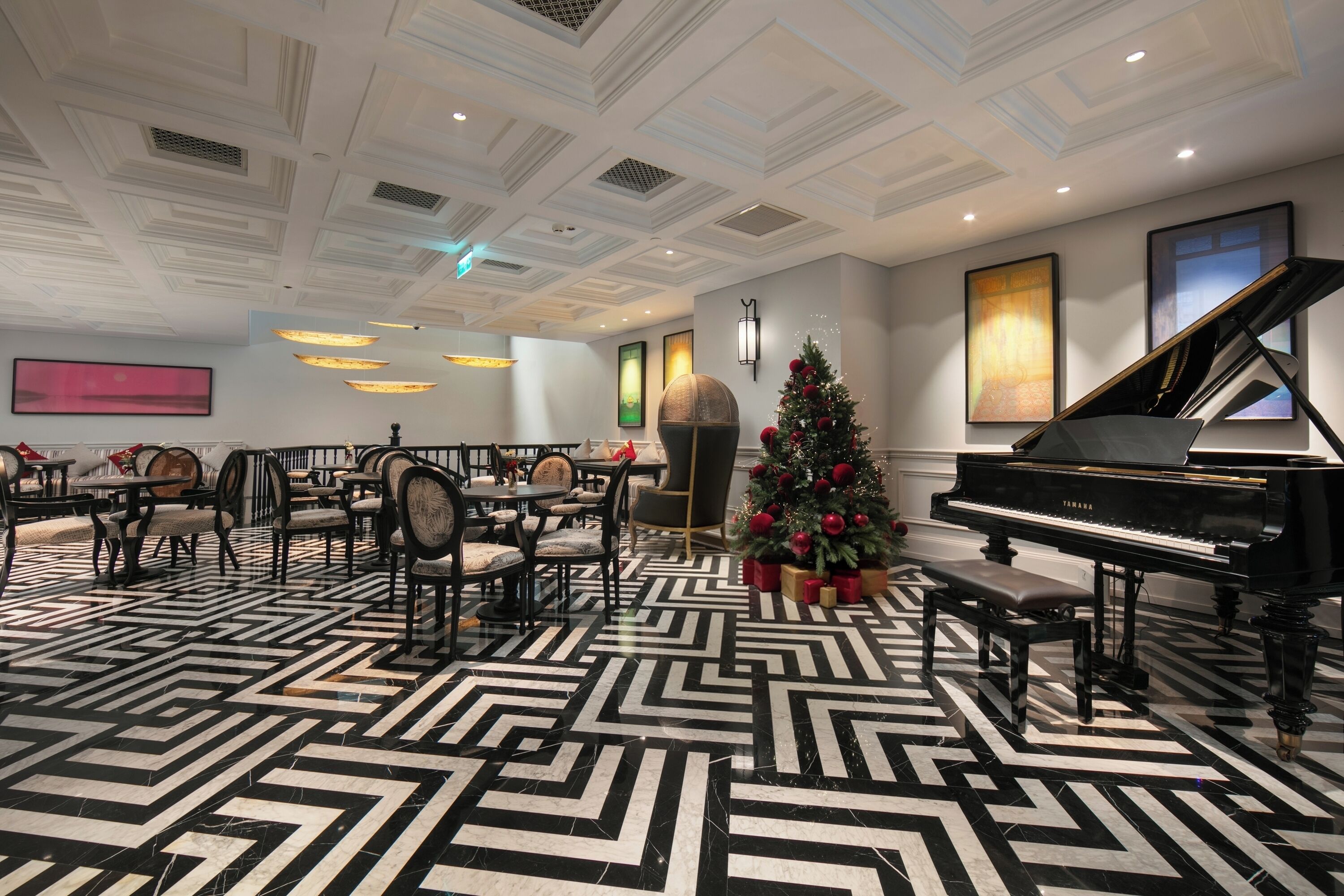 A spacious lobby with a grand piano, a Christmas tree, and a patterned floor.