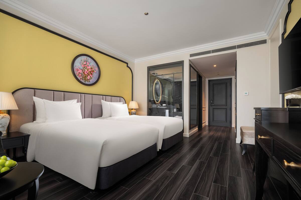 Una habitación de hotel con una cama grande, mesitas de noche, un escritorio y una silla.