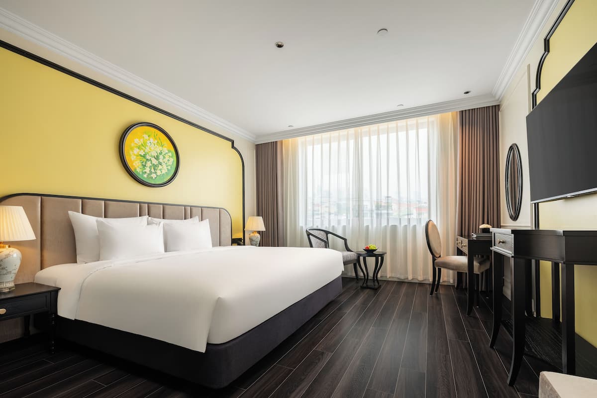 Habitación de hotel con una cama grande, un escritorio, una silla y un televisor.