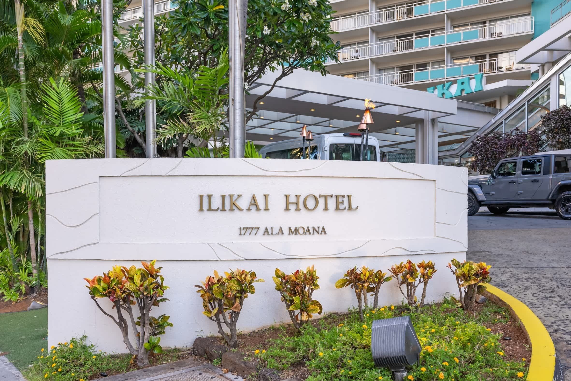 L'esterno dell'Hotel Ilikai, con un cartello, un giardino curato e un edificio moderno sullo sfondo.
