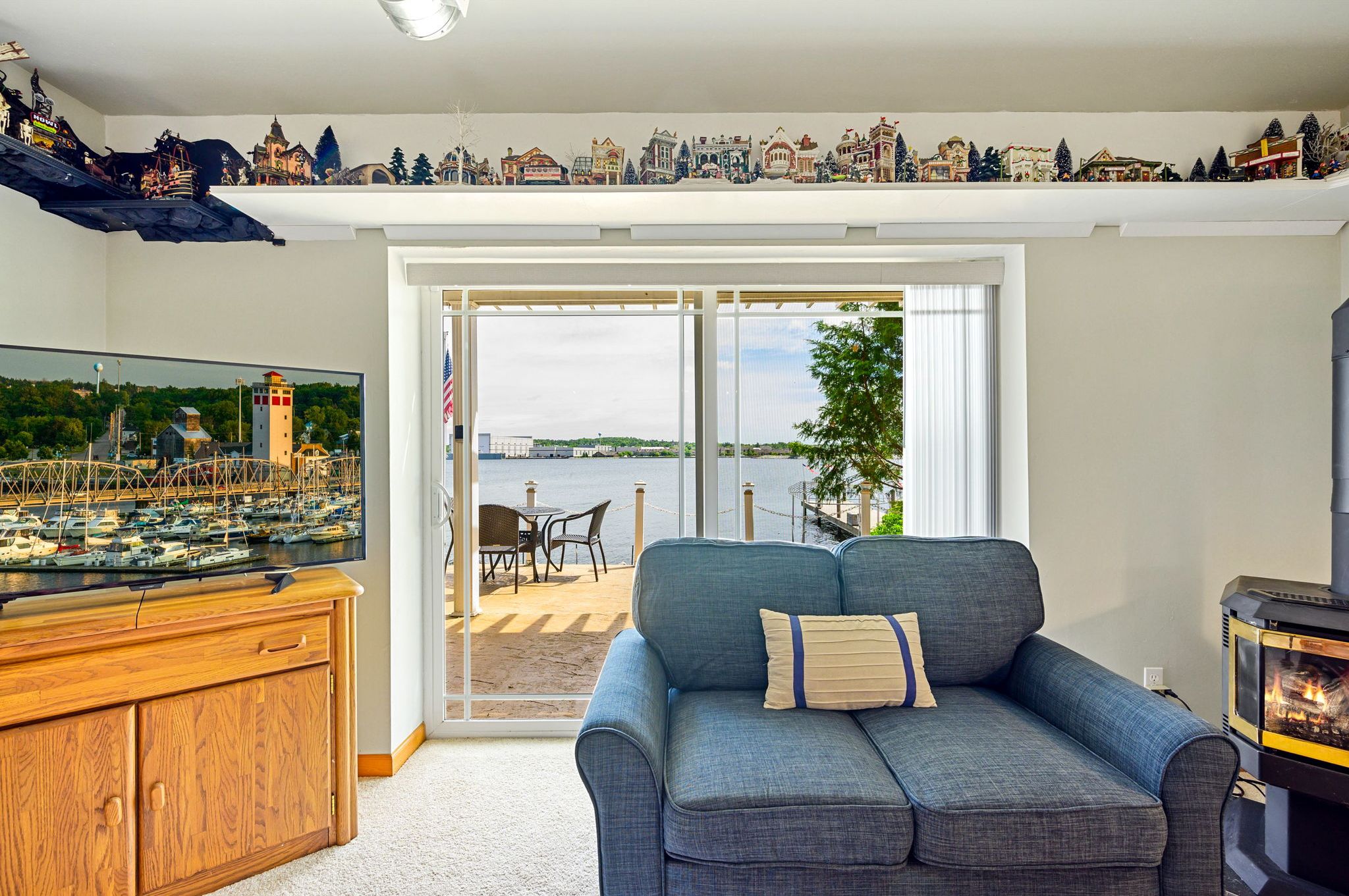 A living room with a large TV, a blue sofa, a wooden cabinet, and a fireplace.