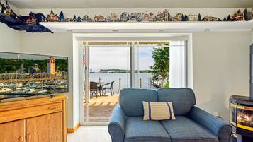 A living room with a large TV, a blue sofa, a wooden cabinet, and a fireplace.