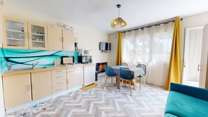 A compact kitchen with a dining area, a TV, and a sofa. - Nid Douillet Terre et Mer (Saint-Hilaire-de-Riez)
