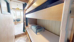 A bunk bed room with a small table and chairs in the background. - Nid Douillet Terre et Mer (Saint-Hilaire-de-Riez)