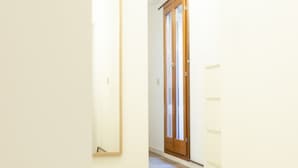 Een gang met een houten deur en een spiegel aan de muur.