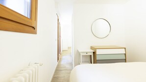 Een hotelkamer met een bed, nachtkastje, spiegel en radiator.